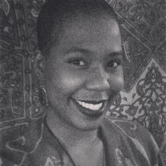 Black and white portrait of a smiling woman, adorned in earrings and patterned fabric