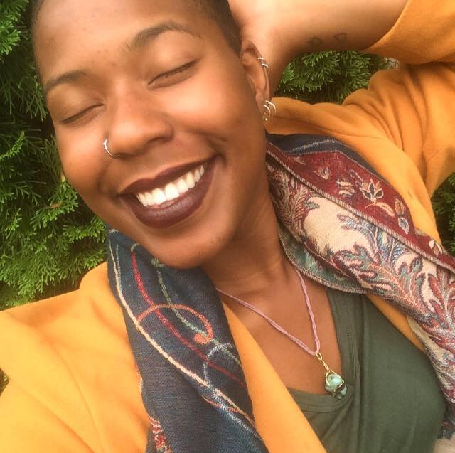 Smiling woman with eyes closed, wearing yellow and patterned scarf, basking in joy