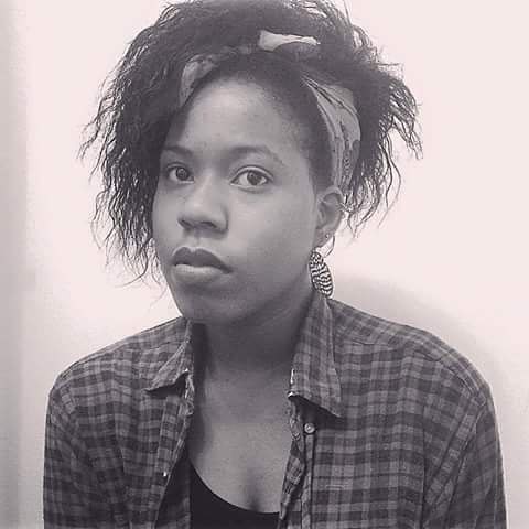Black-and-white portrait of a young woman with a plaid shirt, natural hair tied with a bandana, and a contemplative gaze.