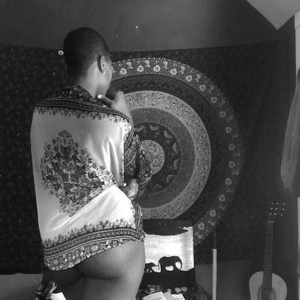 Figure turned away, draped in patterned cloth before a circular tapestry